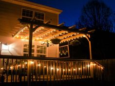 an outdoor deck with lights on it and a pergolated cover over the deck