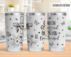 three stainless steel tumblers with crosses and flowers on them