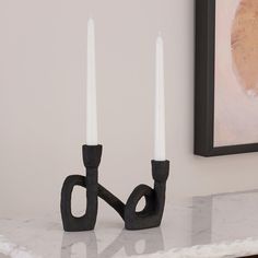 two white candles sitting on top of a marble counter