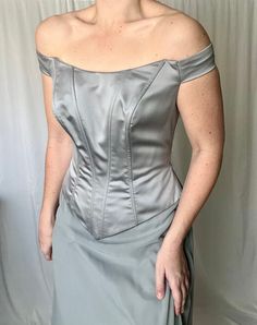 a woman in a gray dress posing for the camera with her hands on her hips