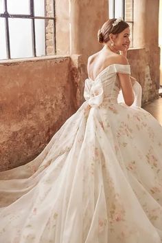 a woman in a wedding dress sitting on the floor with her back to the camera