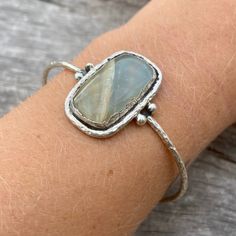 Sterling silver aquateen cuff. Hand made with love! The aquateen has a smooth finish and the silver outline is rather rough, giving the cuff an organic and natural touch. Cuff width: 65 mm (slightly adjustable) Gemstone height: 28mm Gemstone width: 18mm Take a look at our Pebbles & Chance ETSY store https://www.etsy.com/es/shop/pebblesandchance to combine it with other unique, raw, beautiful, precious pieces! Follow us on Instagram! https://www.instagram.com/pebblesandchance/?hl=es Chrysoprase Jewelry, Chrysoprase Ring, Forever Rings, Signature Necklace, Smokey Quartz, Silver Hoop Earrings, Wedding Earrings, Necklace Designs, Cuff Bracelet