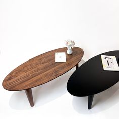 two coffee tables sitting next to each other in front of a white wall with flowers on top