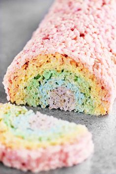 there is a cake that has been cut in half and the inside is colored pink, green, yellow and blue