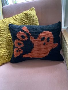 two knitted pillows on a pink couch