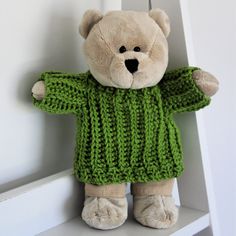 a stuffed teddy bear wearing a green sweater