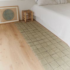 a white bed sitting next to a wooden floor in a bedroom on top of a hard wood floor