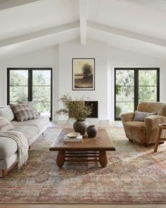 a living room with couches, chairs and a coffee table in front of two windows