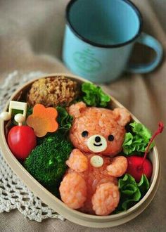 a small teddy bear sitting in a bowl filled with veggies and meats