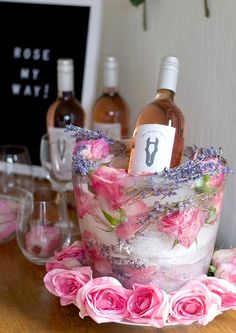 a bottle of wine sitting on top of a cake covered in pink roses and lavenders