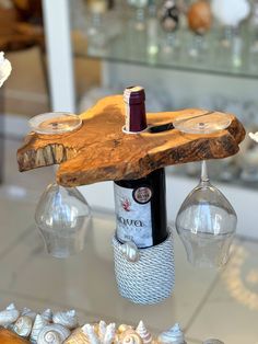 a bottle of wine sitting on top of a wooden table with seashells around it