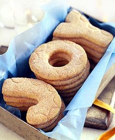 some donuts are in a box with blue paper on the bottom and one is shaped like a number