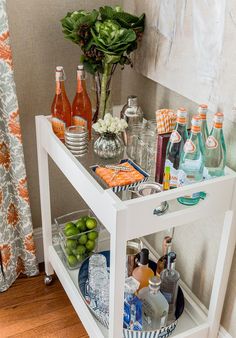 a white table with drinks on it and other items sitting on top of the table