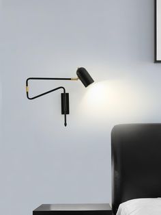 a black lamp is on the wall next to a bed