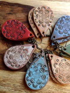 six different colored leather guitar picks on a wooden surface