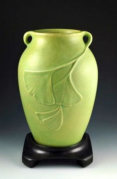 a green vase sitting on top of a wooden stand