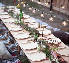 a long table is set with plates and place settings for an outdoor dinner or party