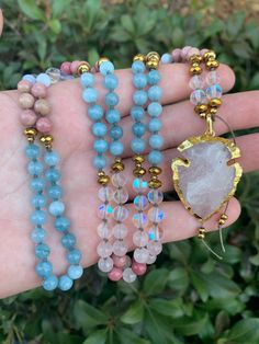 This mala necklace is hand knotted with Aquamarine, Rainbow Mystic Aura Quartz, Rose Quartz, Haitian Flower Rhodonite, and Blue Chalcedony. Gold Hematite Spacers throughout. The pendant is made from gold plated rose Quartz arrowhead. If you have any questions or if you would like a custom mala, please send me a direct message through Etsy & I am happy to help :) PACKAGING: Each mala bead necklace is handmade by me in my crystal studio with love and light. I sage and cleanse each piece with Palo Santo or sage prior to shipping.  💖GEMSTONE HEALING PROPERTIES💖 GOLD HEMATITE: focuses energy and emotions for balance between the body, mind and spirit. Dissolves negativity and prevents you from absorbing the negativity of others. AQUAMARINE: Its calming energies reduce stress and quiet the mind Spiritual Style Faceted Round Beaded Necklaces, Spiritual Style Round Faceted Beads Necklace, Healing Beaded Necklaces With Round Natural Stones, Healing Beaded Necklaces With Natural Stones And Round Beads, Bohemian Crystal Necklace With 8mm Round Beads, Pink 8mm Bohemian Beads, Bohemian 8mm Beads For Jewelry Making, 8mm Bohemian Beads For Jewelry Making, Faceted Beads For Meditation