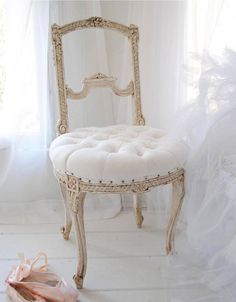 a white chair sitting next to a pair of ballet shoes