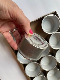 a person is picking up some food from an open box with empty cups in it