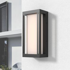 an outdoor light mounted on the side of a wall next to a house with shutters