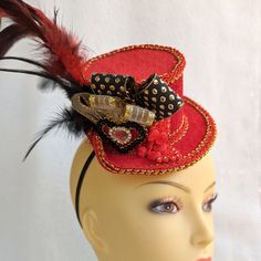 Red velour mini top hat Fascinator decorated with red and gold trims, ribbons, red coque tail feathers, and embellishments.  It features a red velour heart with a crystal embellishment, and gold/black trim edges.  Great accessory for a Mad Hatter or Alice in Wonderland party. Can also be worn at the races or any costume party. It holds to the head with a black elastic band. Place the elastic at the back of your head under your hairline. Handmade in Australia. Laura Lucci's Collection Adjustable Mini Hats For Mardi Gras Costume, Red Carnival Costume Hats And Headpieces For Party, Red Carnival Party Costume Hats And Headpieces, Red Tall Crown Costume Hat For Party, Adjustable Red Hat For Carnival, Red Adjustable Hat For Costume Party, Adjustable Red Hat For Costume Party, Red Headband For Costume, Red Costume Accessories For Mardi Gras