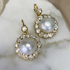 An amazing pear of cluster earrings featuring two saltwater natural round button pearls weighing 7.89 carats and 8.07 carats. Surrounding the pearls is a cluster of old European cut diamonds. The total approximate weight of the diamonds is 4.80 carats. These earrings are made in 18k yellow gold and have Euro-backs.
The measurements of the pearls are 11.20mm. The measurements including the diamond cluster are 18.40mm.
If you have any questions about the Tabor earrings, please feel free to contact us. Luxury Vintage Yellow Gold Pearl Earrings, Luxury Yellow Gold Victorian Pearl Earrings, Pear-shaped Pearl Drop Diamond Earrings, Pear-shaped Diamond Earrings With Pearl Drop, Vintage Diamond Pearl Earrings For Wedding, Exquisite Pearl Drop Round Diamond Earrings, Victorian White Pearl Earrings For Formal Occasions, Victorian Pearl Drop Earrings For Formal Occasions, Wedding Round Pearl Earrings