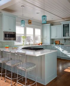 a kitchen with blue cabinets and an island in the middle, surrounded by stools