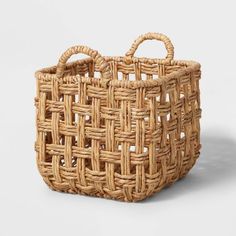 an empty woven basket with handles on a white background and the handle is made out of wicker