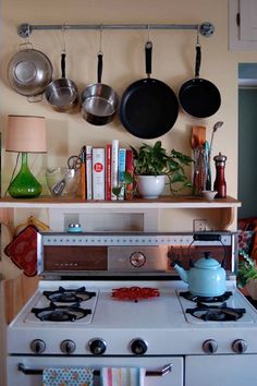 a stove with pots and pans hanging on the wall