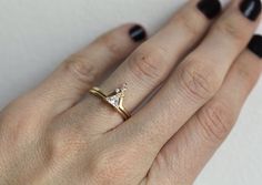 a woman's hand wearing a gold ring with two small white diamonds on it