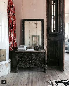 a room with wooden floors and a mirror on top of the table next to it