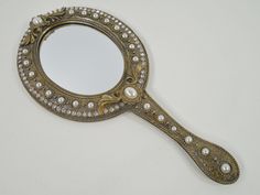 an antique looking mirror with pearls on the side and a small round mirror in the middle