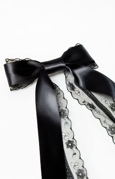 a black ribbon tied to a white wall with lace on it's sides and an open zipper at the end