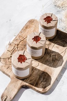 three small round boxes with wax on them are sitting on a wooden tray in the snow