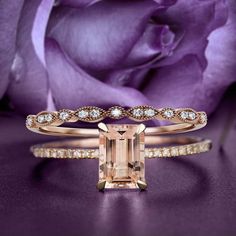 an engagement ring and wedding band set in yellow gold with a pink rose behind it