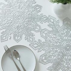 a white plate and silverware on a table with snowflakes cut out of paper