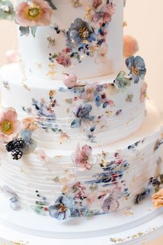 a three tiered white wedding cake with flowers on it