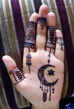 a person's hand with hendi tattoos on it and the moon in the middle