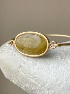 This gorgeous bangle bracelet is plated in gold and features green amber stones set in a size 7 It radiates elegance and sophistication, and makes a stunning statement piece for any outfit. This product is unique due to the stone and is presented as a single instance. Weight - 0,27 Oz Length - 1.18 Size(US)- 7 Material - gold plated sterling silver and natural amber Adjustable Oval Jewelry Tarnish Resistant, Tarnish Resistant Adjustable Oval Jewelry, Adjustable Oval Tarnish-resistant Jewelry, Luxury Cabochon Bangle Jewelry, Luxury Oval Gemstone Bangle, Modern Oval Amber Jewelry, Luxury Oval Brass Jewelry, Modern Amber Oval Jewelry, Adjustable Gold Gemstone Jewelry