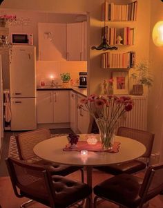 a small kitchen with a table and chairs in the center, next to a refrigerator