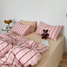 a teddy bear sitting on top of a bed covered in pink and brown striped sheets