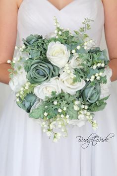 a bride holding a bouquet of white and green flowers