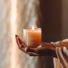 a woman holding a lit candle in her hand with an inspirational quote on the front