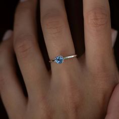 a woman's hand with a ring on it and a blue stone in the middle