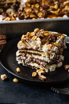 a piece of tirami cake on a black plate with some nuts around it