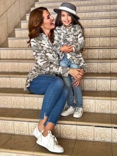 a woman sitting on the steps with her child in her lap and smiling at each other