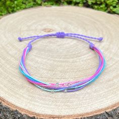 Lovely handmade bracelet, made from waxed cord in fresh colors - purple, blue and pink tones - and decoration of small silver lined seed beads. The bracelet fastens with a sliding knot so you can adjust the size to fit perfectly. Minimum diameter when it's closed is 15-16cm. and the fastening threads allows it to be opened to around 28-30cm. The waxed cord thickness is 1mm. If you need specific size please let us know, custom orders are welcome, feel free to contact us with any questions. All of our bracelets are 100% handmade, we don't sell anything that is not crafted by us. Created with love for you! Purple Resizable Friendship Bracelets, Multicolor Adjustable Nylon Cord Friendship Bracelets, Adjustable Multicolor Nylon Cord Friendship Bracelets, Pink Nylon Cord Bracelets For Beach, Adjustable Purple Braided Bracelets For The Beach, Purple Bracelet With Sliding Knot For Beach, Purple Bracelets With Adjustable Cord, Adjustable Purple Bracelet With Cord, Multicolor Braided Bracelet With Adjustable Waxed Cord