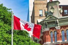 the canadian flag is flying in front of some buildings