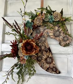 a wooden horse head decorated with flowers and greenery on the front door to a house